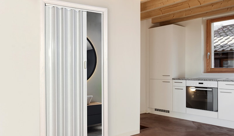 Folding door separating a bathroom from a kitchen
