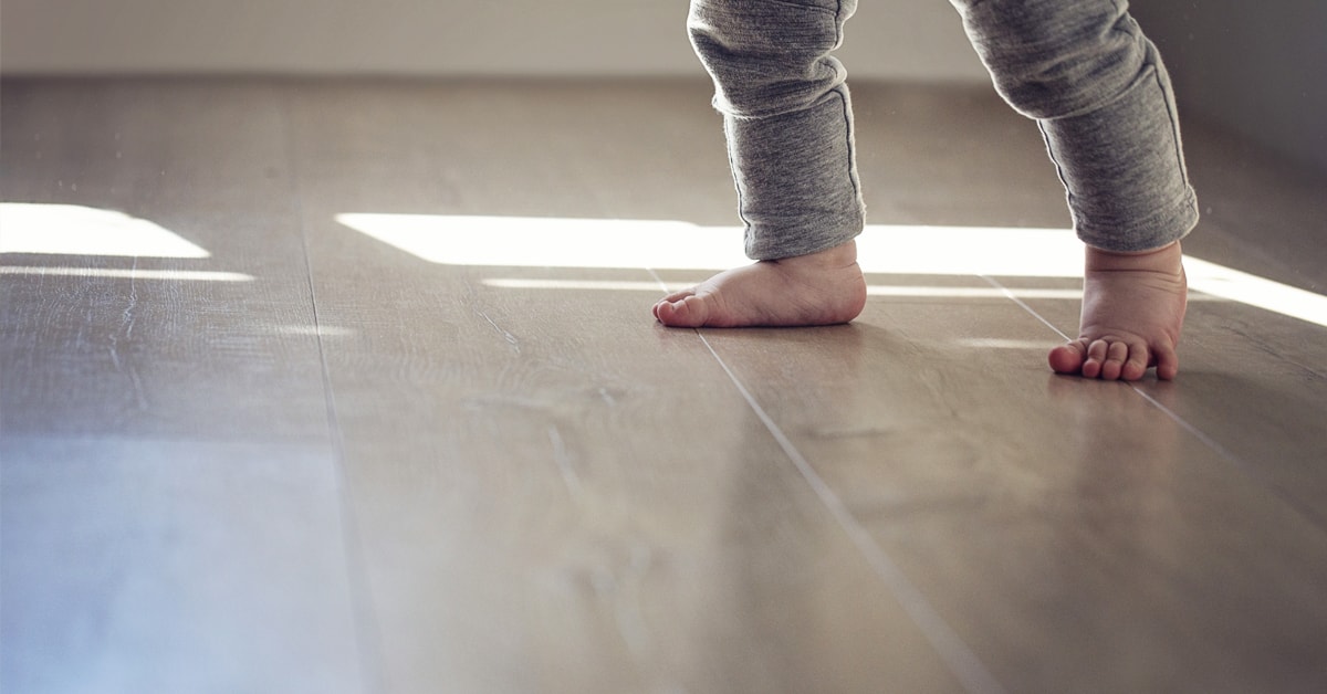 Enfant qui marche nu pied sur un plancher gris