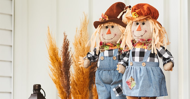 Two decorative scarecrows on a porch