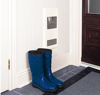Rain boots placed on the floor next to a wall heater