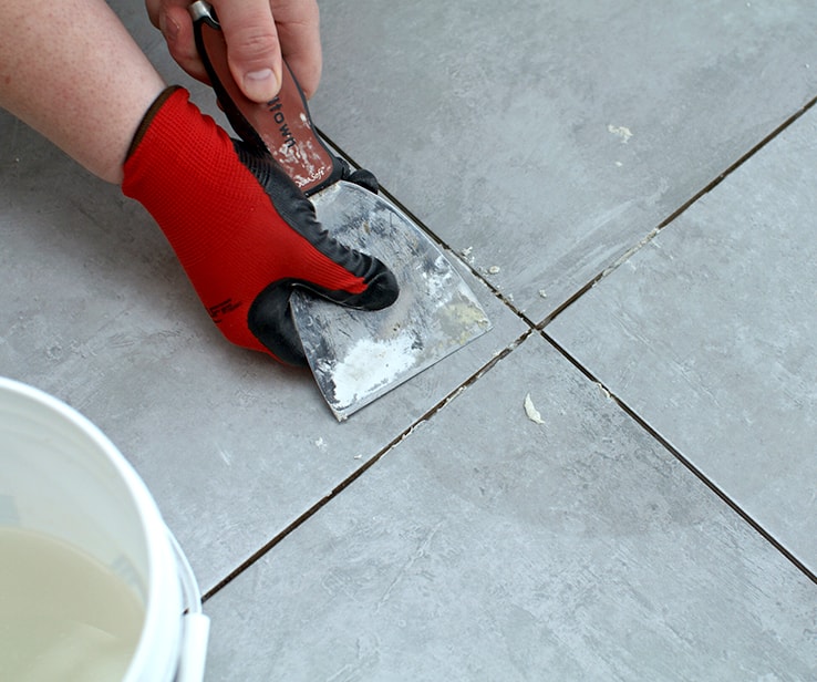 Man removing excess mortar on a tiled floor